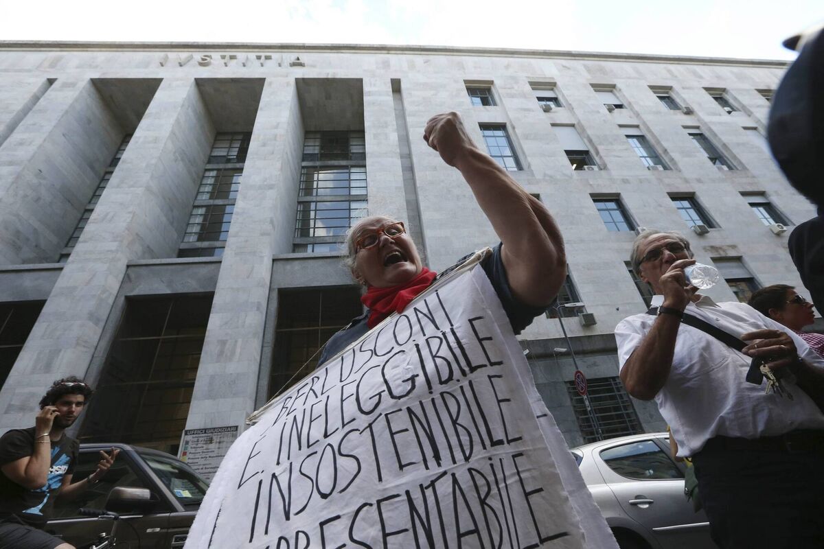 A woman rejoices outside the courthouse after the verdict against Silvio Berlusconi in Milan, June 24, 2013. Former Italian Premier Silvio Berlusconi was convicted of paying for sex with an underage prostitute during infamous "Bunga Bunga" parties at his villa and then using his influence to try to cover it up.  The banner reads in Italian: "Berlusconi is ineligible, unsupportable, unpresentable". AP Photo/Luca Bruno