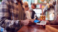 Male Customer Wearing Mask In Bar Making Contactless Payment For Drinks During Health Pandemic
