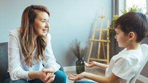 <p>Cheerful young kid talking with helpful child counselor during psychotherapy session in children mental health center. Child counselor during psychotherapy session</p>