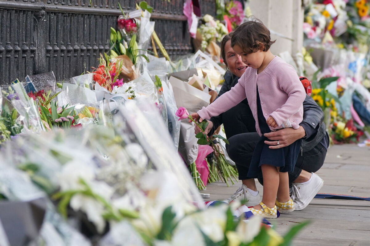 A woman and a child lay a single pink rose by the railings at Buckingham Palace, London, following the death of Queen Elizabeth II on Thursday. Picture: Dominic Lipinski/PA Wire A woman and a child lay a single pink rose by the railings at Buckingham Palace, London, following the death of Queen Elizabeth II on Thursday. Picture: Dominic Lipinski/PA Wire