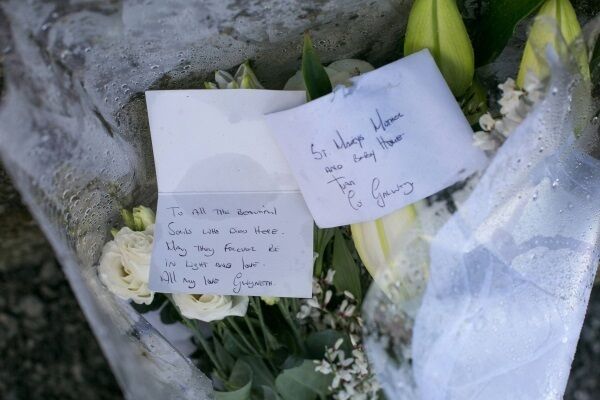 A bouquet of flowers and a card left at the mother-and-babies home in Tuam. It reads: ‘To all the beautiful souls who died here, may they forever be in light and love. All my love, Gwyneth’.