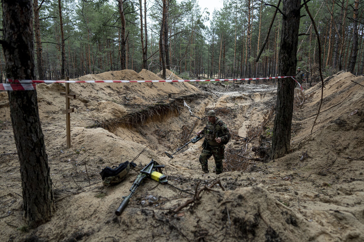A Ukrainian serviceman inspects a mass grave in the recently retaken area of Izium, Ukraine. Picture: Evgeniy Maloletka/AP