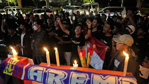 Football fans at a candlelit vigil in Jakarta, Indonesia, for Arema FC Supporters who became victims of Saturday’s tragedy (Dita Alangkara/AP)