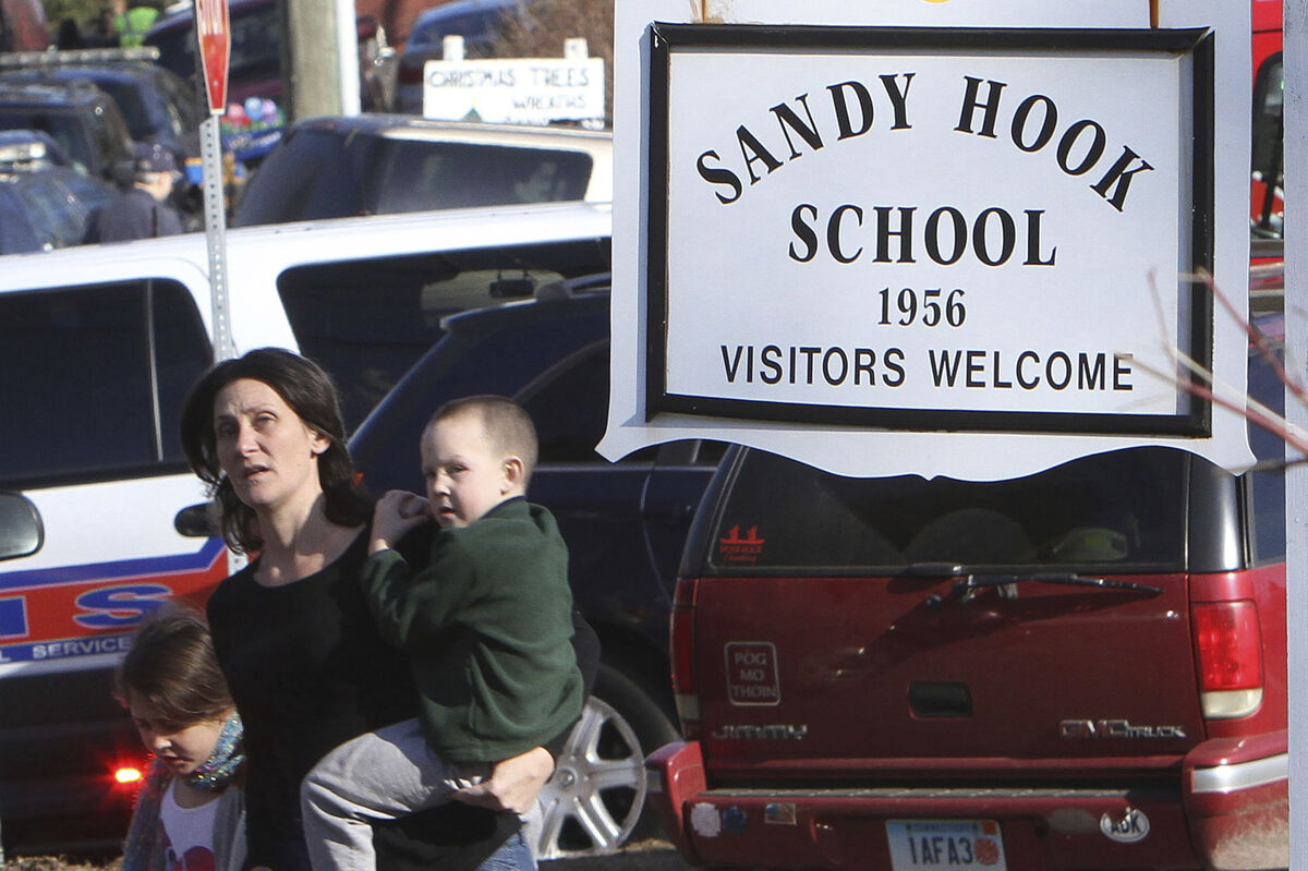 A parent walks away from the Sandy Hook Elementary School with her children following a shooting at the school.