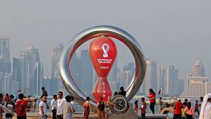 <p>A picture taken on Thursday shows people walking past the Qatar 2022 FIFA World Cup countdown clock as it nears marking 30 days, in the Qatari capital Doha. Picture: Karim JAAFAR / AFP</p>