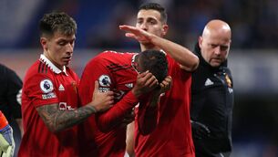 <p>IN TEARS: Manchester United's French defender Raphael Varane (C) is consoled by Manchester United's Argentinian defender Lisandro Martinez (L) and Manchester United's Portuguese defender Diogo Dalot (2nd R) as he leaves the pitch after picking up an injury. Pic: Adrian Dennis/AFP via Getty Images</p>