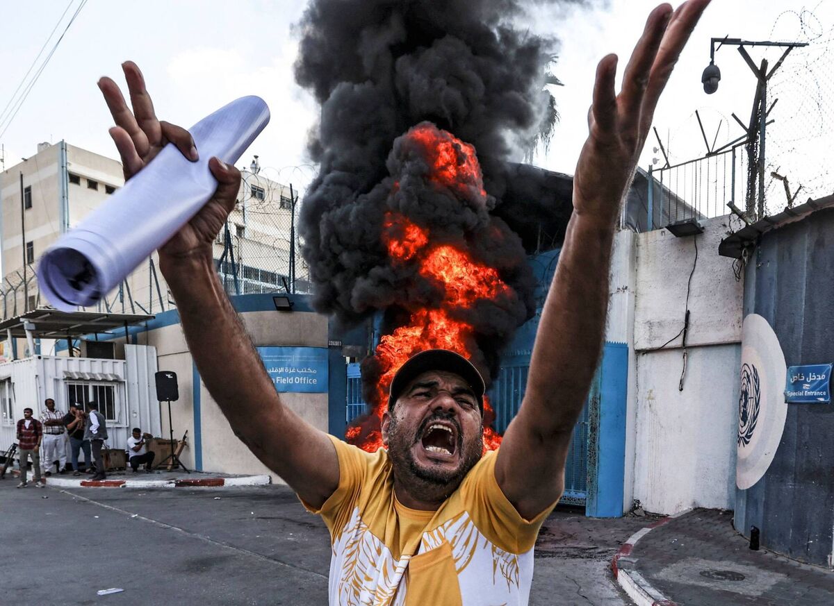 A Palestinian protester chants slogans by tires set aflame by the Gaza City headquarters of the United Nations Relief and Works Agency for Palestine Refugees (UNRWA) on September 19, 2022, during a demonstration demanding that their homes which were destroyed in the 2014 conflict with Israel be rebuilt. Photo by MAHMUD HAMS / AFP A Palestinian protester chants slogans by tires set aflame by the Gaza City headquarters of the United Nations Relief and Works Agency for Palestine Refugees (UNRWA) on September 19, 2022, during a demonstration demanding that their homes which were destroyed in the 2014 conflict with Israel be rebuilt. Photo by MAHMUD HAMS / AFP