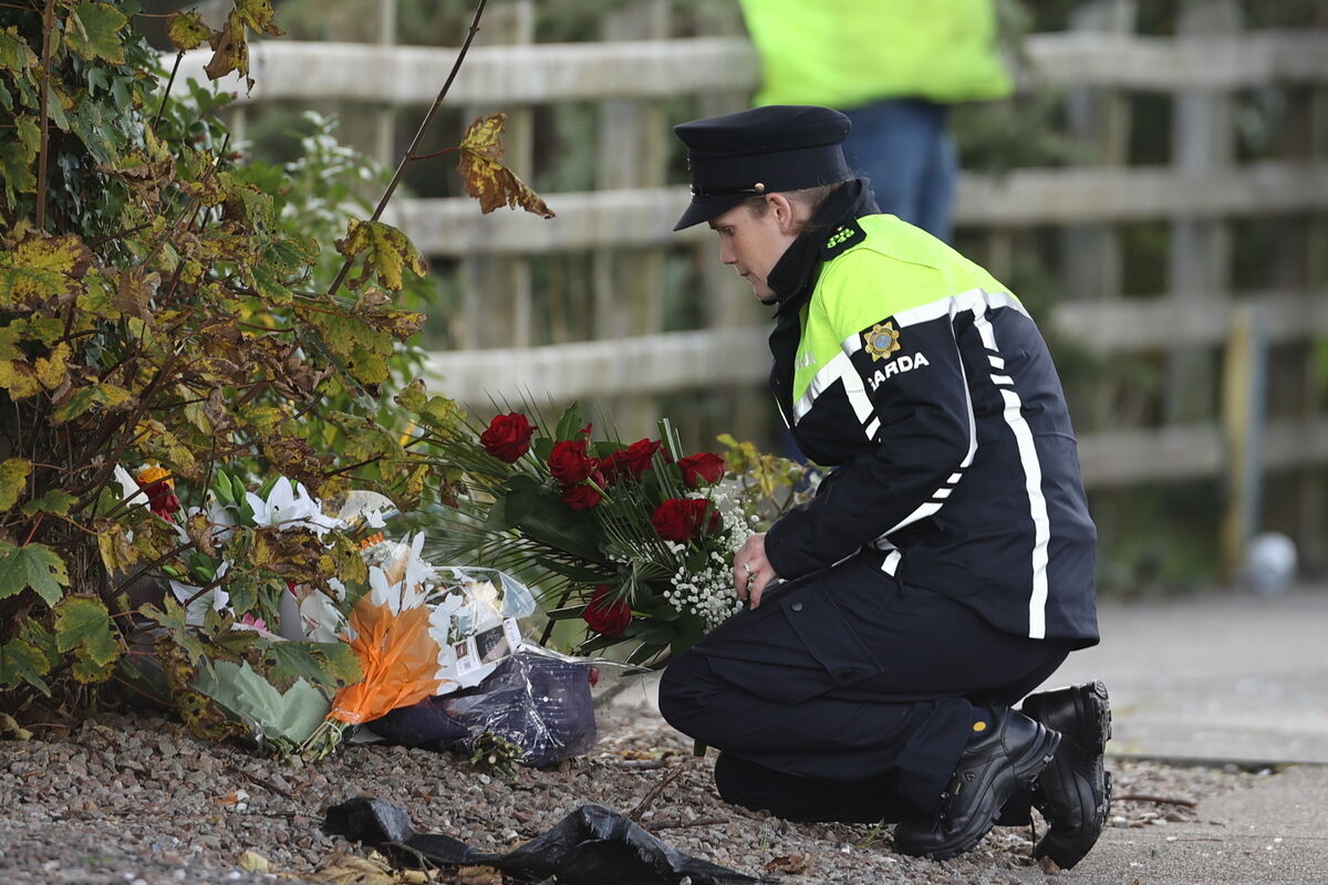 A member of An Garda Síochána lays flowers at the scene.