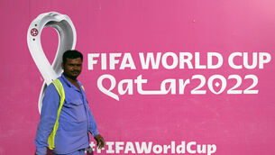 A worker walks past a billboard announcing the upcoming Qatar 2022 FIFA World Cup, in Doha, Qatar, Saturday, Nov. 12, 2022. Final preparations are being made for the soccer World Cup which starts on Nov. 20 when Qatar face Ecuador. (AP Photo/Hassan Ammar)