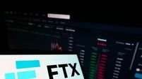 Smartphone with logo of cryptocurrency exchange company FTX Trading on screen in front of business website. Focus on left of pho