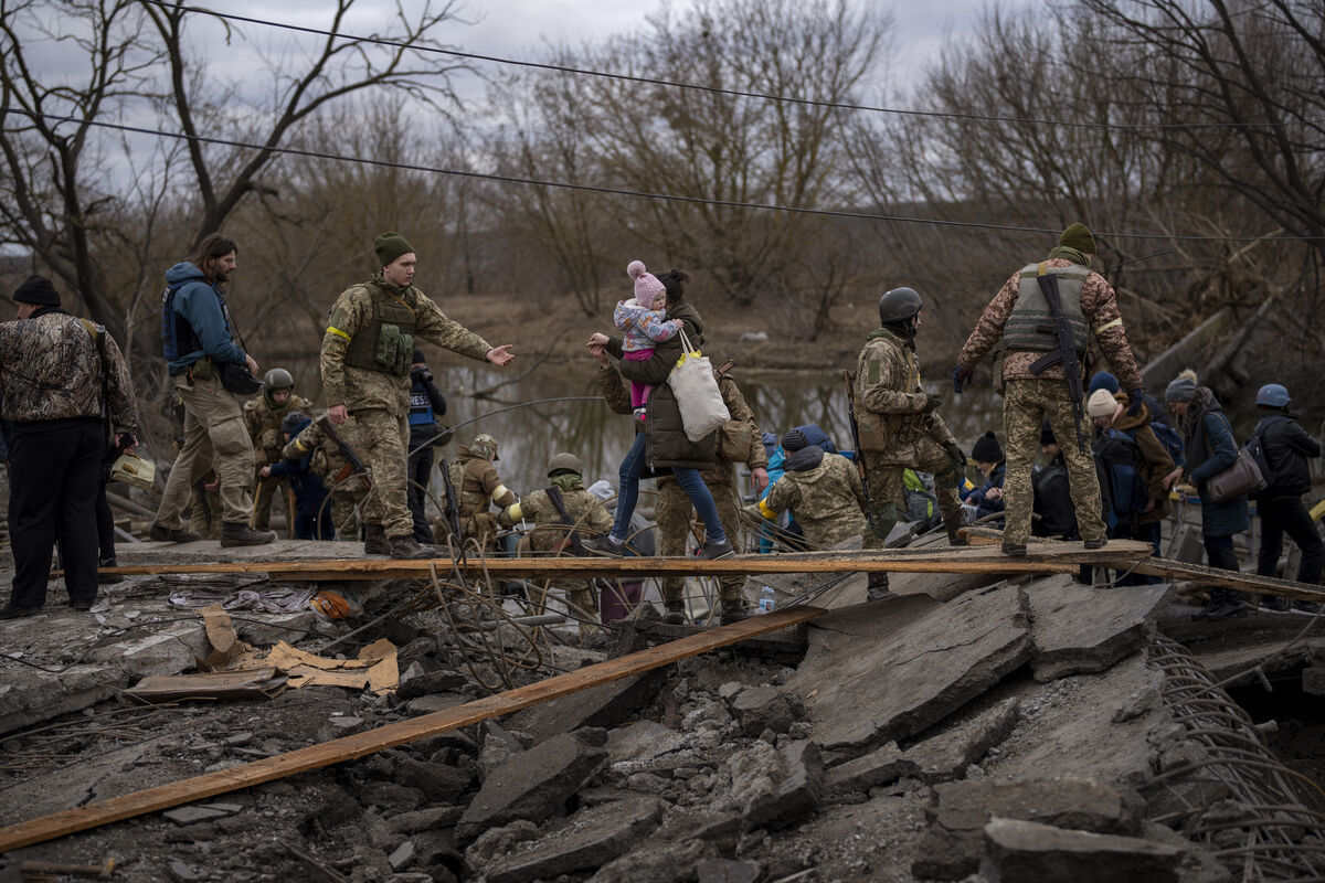 Ukrainian soldiers help a fleeing family crossing the Irpin river in the outskirts of Kyiv, in March. Picture: AP Photo/Emilio Morenatti