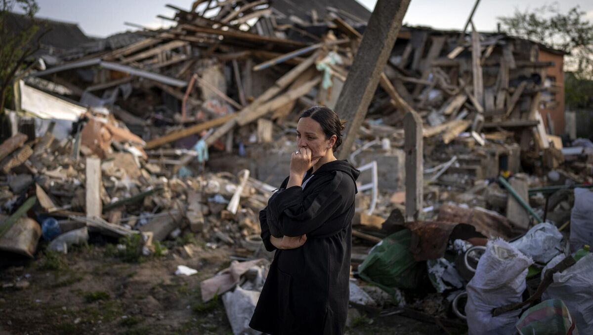 Anna Shevchenko, 35, reacts next to her home in Irpin, near Kyiv, Tuesday, May 3, 2022. The house, built by Shevchenko's grandparents, was nearly completely destroyed by bombing in late March during the Russian invasion of Ukraine. Picture: AP Photo/Emilio Morenatti
