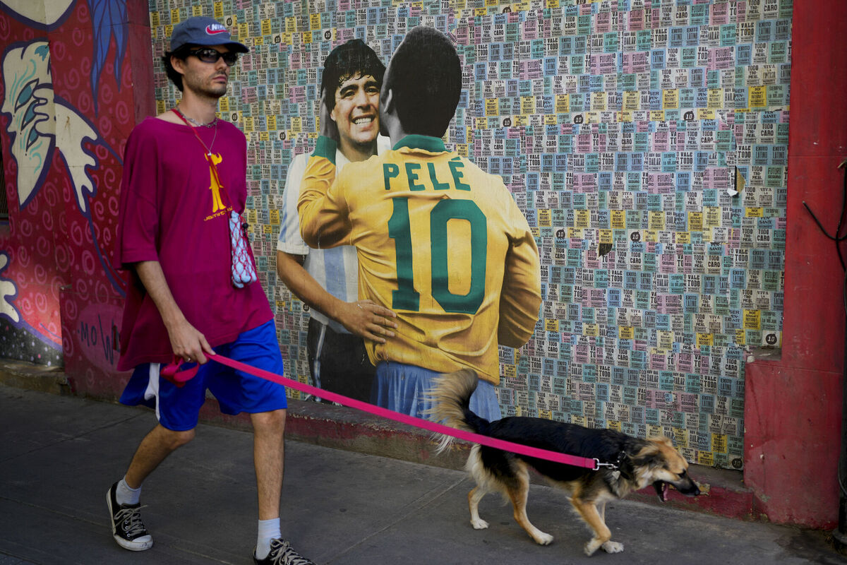 A man walks his dog walk past a mural showing Brazilian soccer legend Pele and Argentina late soccer star Diego Armando Maradona in Buenos Aires. Picture: AP Photo/Natacha Pisarenko