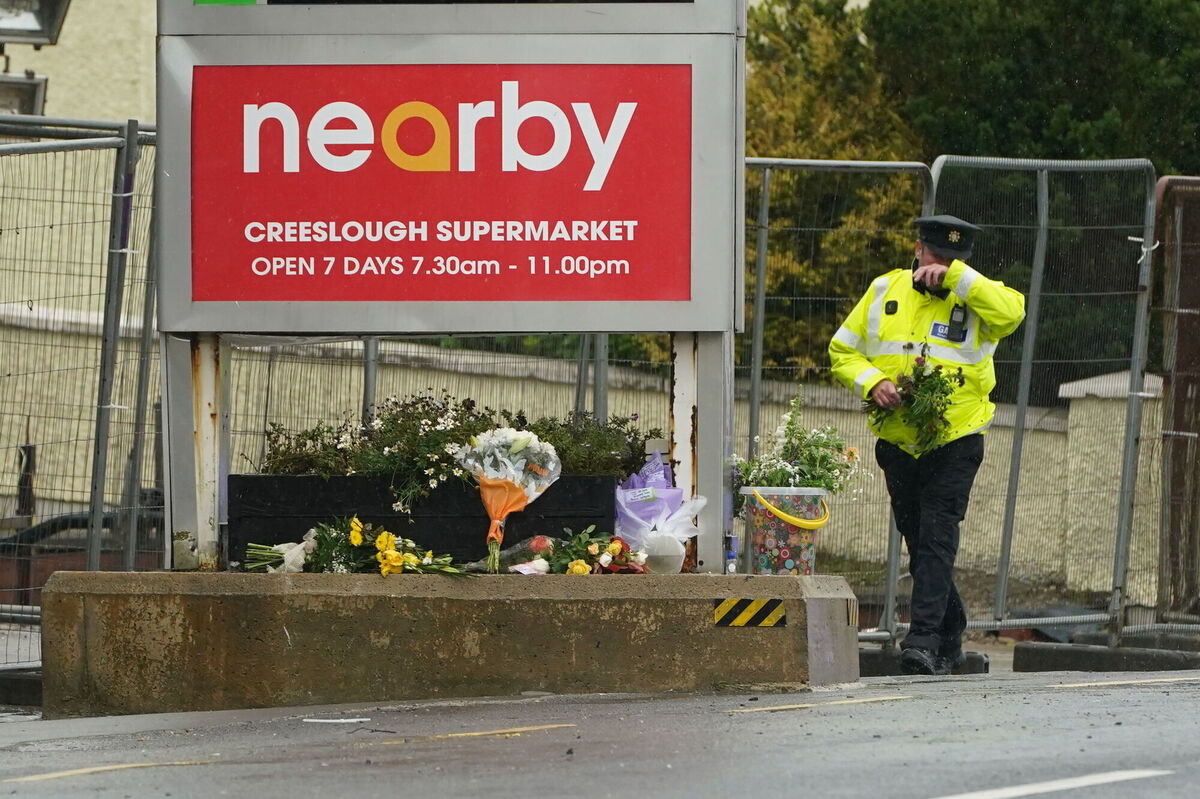 A garda brings flowers to the scene of an explosion at Applegreen service station in the village of Creeslough in Co Donegal. Picture: Brian Lawless/PA Wire