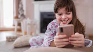 <p>Happy young girl using smartphone and smiling</p>