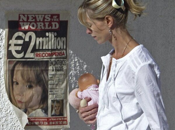 Kate McCann passes by a poster displaying police and news desk’s numbers for their missing daughter.