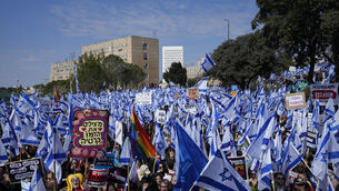 Israelis wave national flags during a protest outside the Knesset in Jerusalem against plans by Prime Minister Benjamin Netanyahu’s new government to overhaul the judicial system (Ohad Zwigenberg/AP)