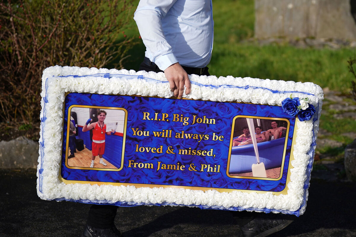 A person carries a floral tribute to John ahead of his funeral mass. Picture: Niall Carson/PA Wire