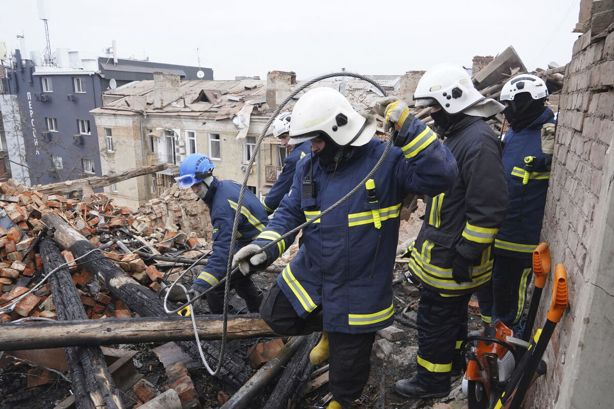 Ukrainian emergency workers clear the rubble on the roof of a residential building that was hit by a Russian rocket in Kharkiv.