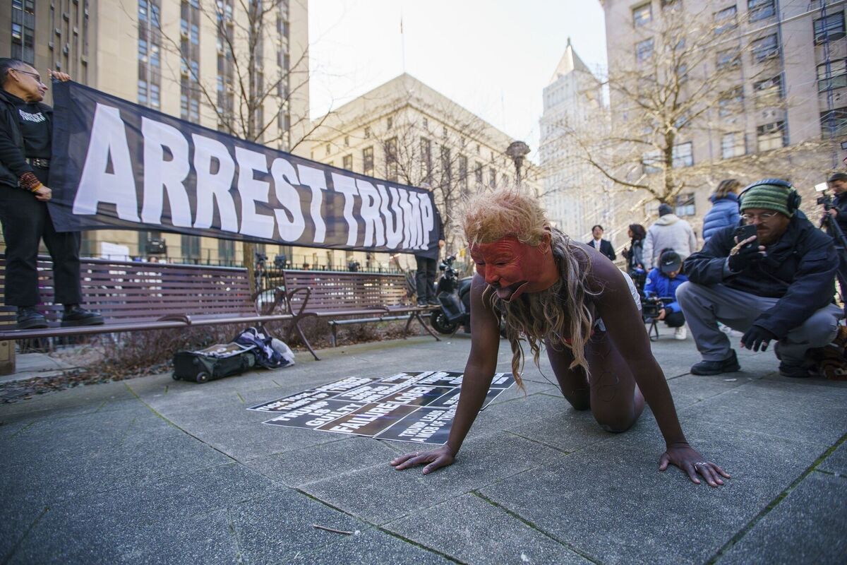 A woman performs with a mask of former president Donald Trump as a small group of people protest near the District Attorney office, Tuesday, March 21, 2023, in New York, in an anticipation of former president's possible indictment. (AP Photo/Eduardo Munoz Alvarez)
