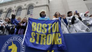 <p>STRONG: Carlos Arredondo, a 2013 Boston Marathon first-responder, holds a 'Boston Strong' banner in the grandstand near the 2015 Boston Marathon finish line. Pic: AP Photo/Elise Amendola</p>