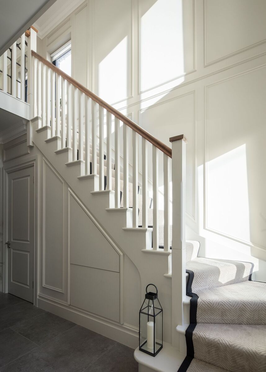  The elegant staircase carries the panelled wall look upward and is carpeted in neutral herringbone bound in black.