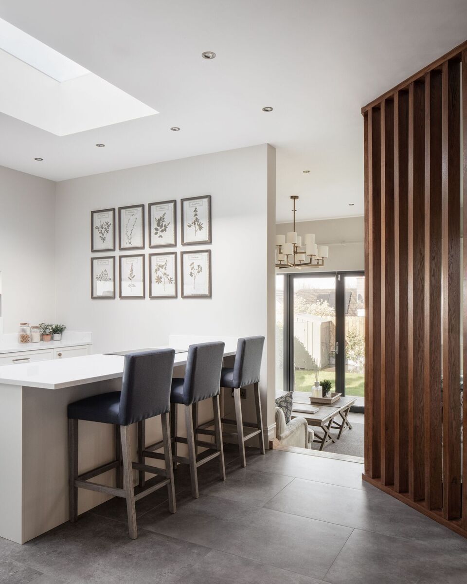  A slatted wooden screen semi-shields the kitchen from the lower-level living and TV room beyond.