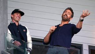 <p>Wrexham co-owners Rob McElhenney (left) and Ryan Reynolds react in the stands during the Vanarama National League win over Boreham Wood (Martin Rickett/PA)</p>