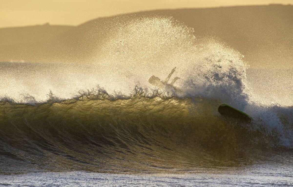 A surfer takes a tumble backlit by the evening sun at Garrettstown Beach, Cork. Picture: Dan Linehan