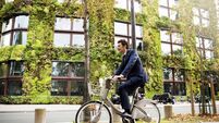 Man riding bike in front of vertical garden