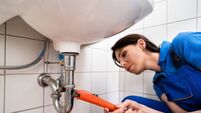 Plumber Fixing A Sink In Bathroom