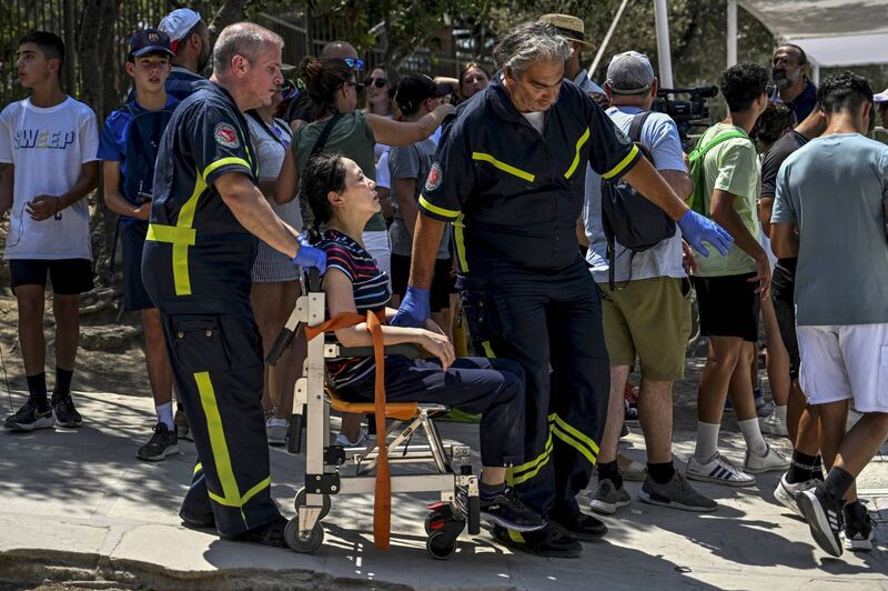Rescue workers transport a visitor from the archaeological site of the Acropolis to an ambulance.
