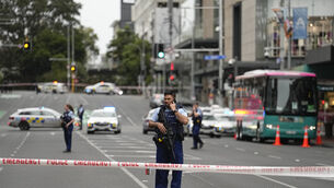 <p>Armed New Zealand police officers stand at a road block in the central business district following a shooting in Auckland, New Zealand (Abbie Parr/AP)</p>