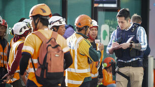 Police interview construction workers in the central business district following a shooting in Auckland (New Zealand Herald via AP)