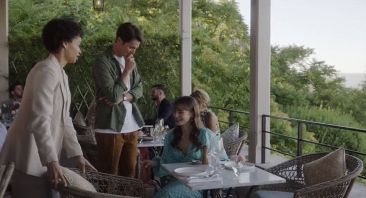 Emily in Paris Season 3: Emily sits on the stool that was placed for her bag. Picture: Netflix Emily in Paris Season 3: Emily sits on the stool that was placed for her bag. Picture: Netflix