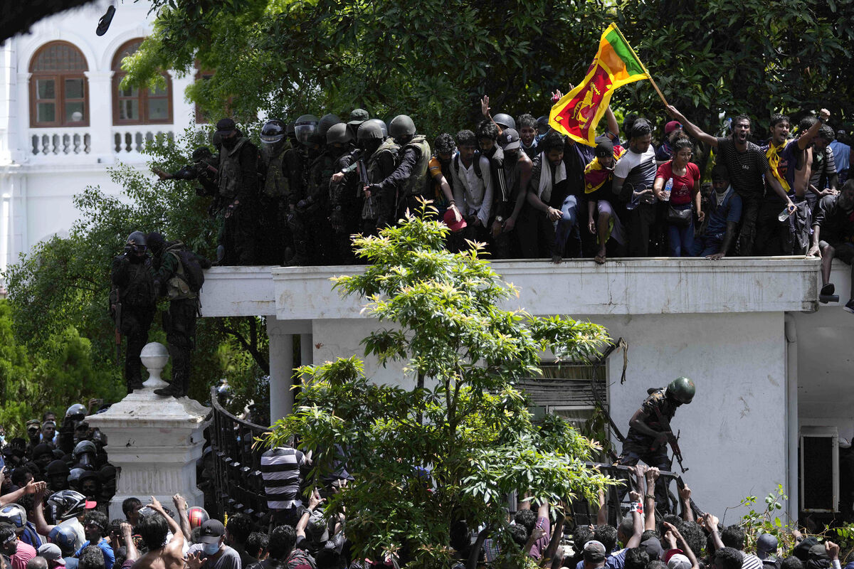 Protesters, one carrying national flag, storm the Sri Lankan prime minister Ranil Wickremesinghe's office, demanding he resign after president Gotabaya Rajapaksa fled the country amid economic crisis in Colombo, Sri Lanka, on July 13, 2022. Picture: Eranga Jayawardena/AP