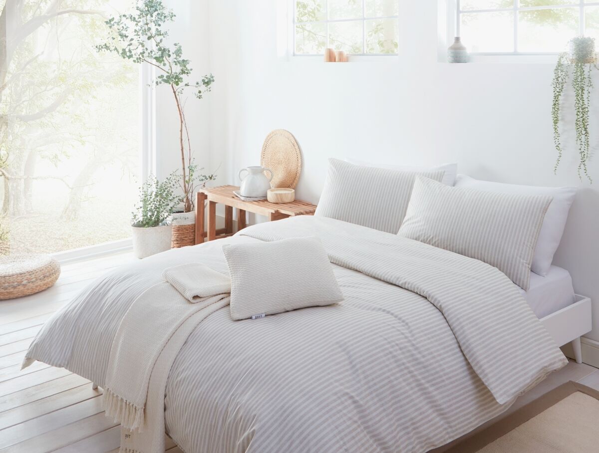 A white guestroom with a wall of glass retains a celestial sense of utter calm. A low bed frame with kick-out legs and an unusual vintage table have been deployed rather than a standard height divan and locker. Linens by French Bedroom in Breton Cloud Stripe. A white guestroom with a wall of glass retains a celestial sense of utter calm. A low bed frame with kick-out legs and an unusual vintage table have been deployed rather than a standard height divan and locker. Linens by French Bedroom in Breton Cloud Stripe.