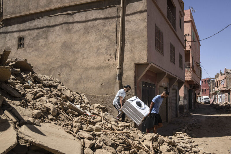 People recover a washing machine from their home that was damaged by the earthquake. Picture: AP People recover a washing machine from their home that was damaged by the earthquake. Picture: AP