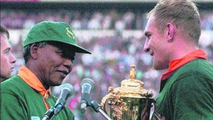 <p>South Africa captain Francois Pienaar receives the Rugby World Cup trophy from president Nelson<br class="HardReturn">Mandela, wearing a Springboks jersey, after their victory over New Zealand on June 24, 1995. Pic: Ross Setford/AP</p>