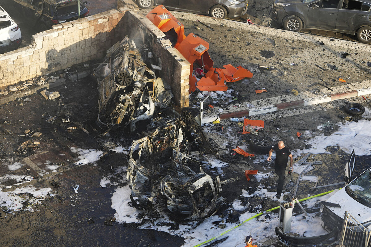 Israeli firefighters extinguish fire after a rocket fired from the Gaza Strip hit a parking lot in Ashkelon, southern Israel (Picture: AP /Tsafrir Abayov)