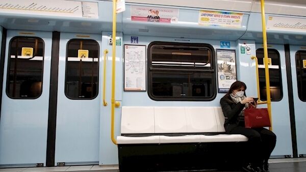 A woman wearing a face mask checks her phone in a subway in Milan, Italy, Tuesday, Feb. 25, 2020. (AP Photo/Antonio Calanni)