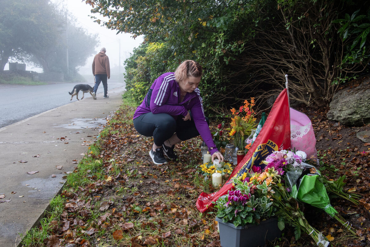 Sam Byrne places a candle at the scene where her partner Seán Feeney passed away from a suspected heart attack, while chasing teens who had been throwing stones at his house in Cobh. Picture: Dan Linehan