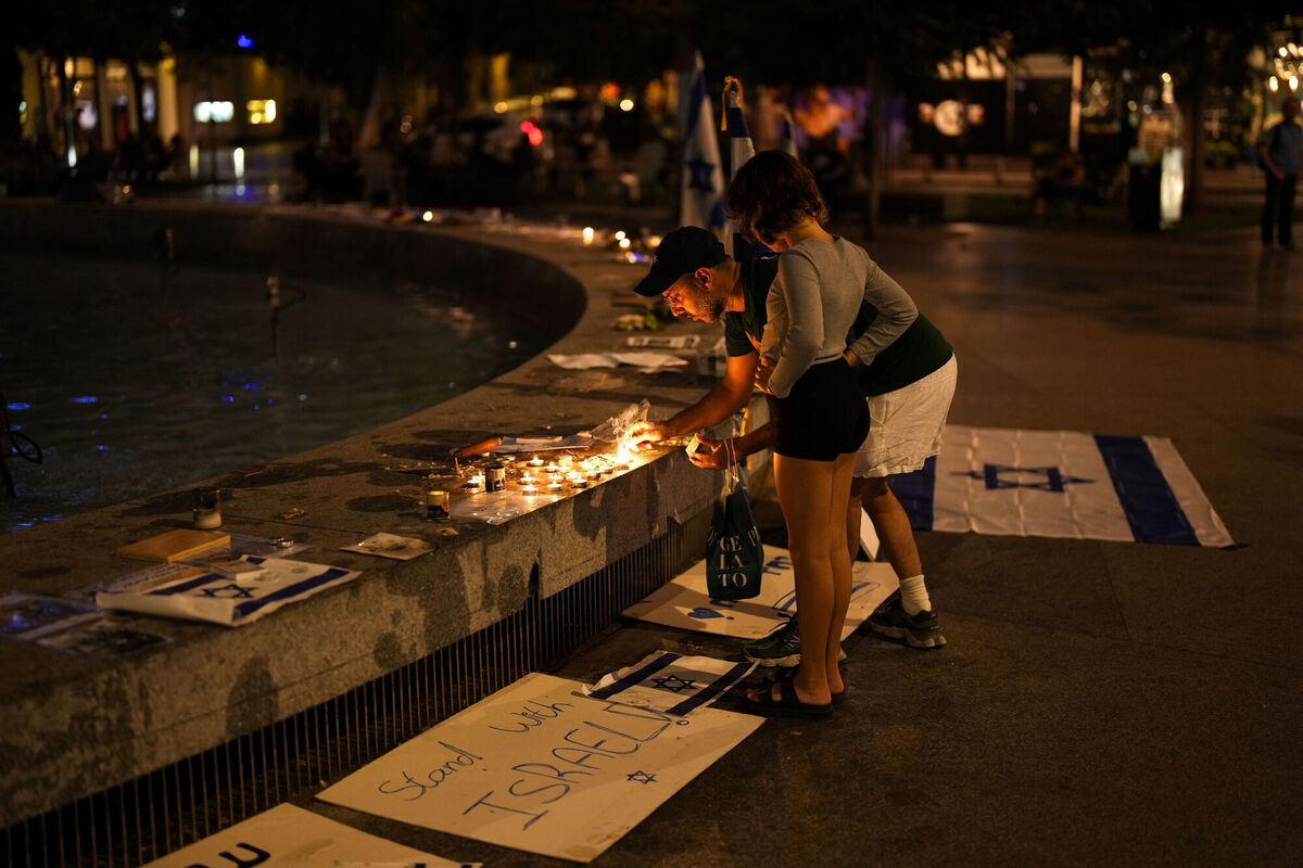 A man lights candles to honor the victims of the Hamas attacks, at Dizengoff square in central Tel Aviv, Israel, Friday, Oct. 27, 2023. (AP Photo/Francisco Seco)