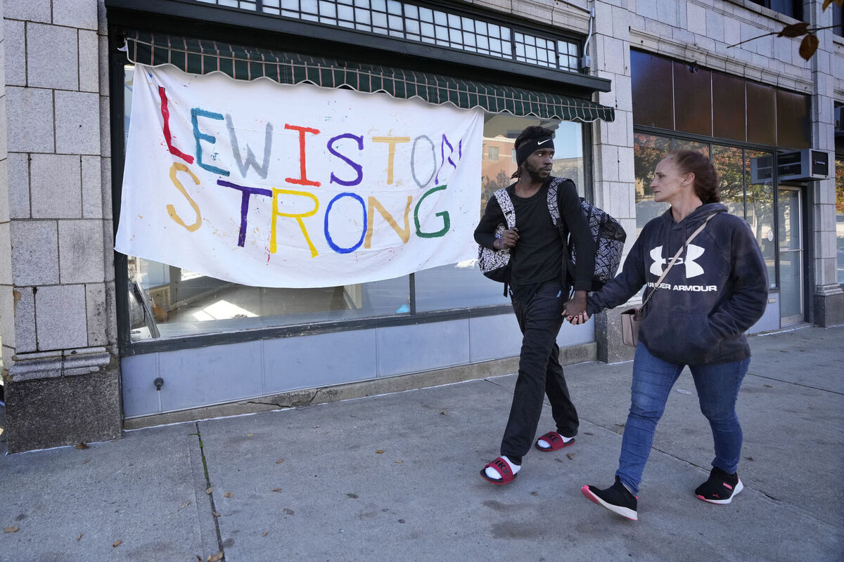 A couple walks by a banner that was put up in response to this week's deadly mass shootings, in Lewiston, Maine. Police are still searching for the suspect who killed at least 18 in separate shootings at a bowling alley and restaurant on Wednesday. Picture: AP Photo/Robert F. Bukaty
