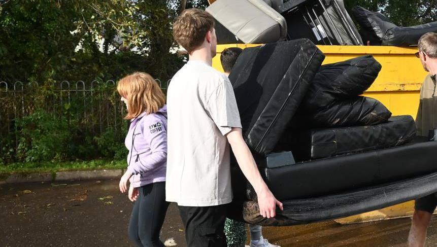Residents fill a skip with flood damaged items from their homes after Storm Babet hit on Wednesday. The residents of Copper Valley Vue in Glanmire, Cork, faced a major cleanup after flood water hit their homes. 