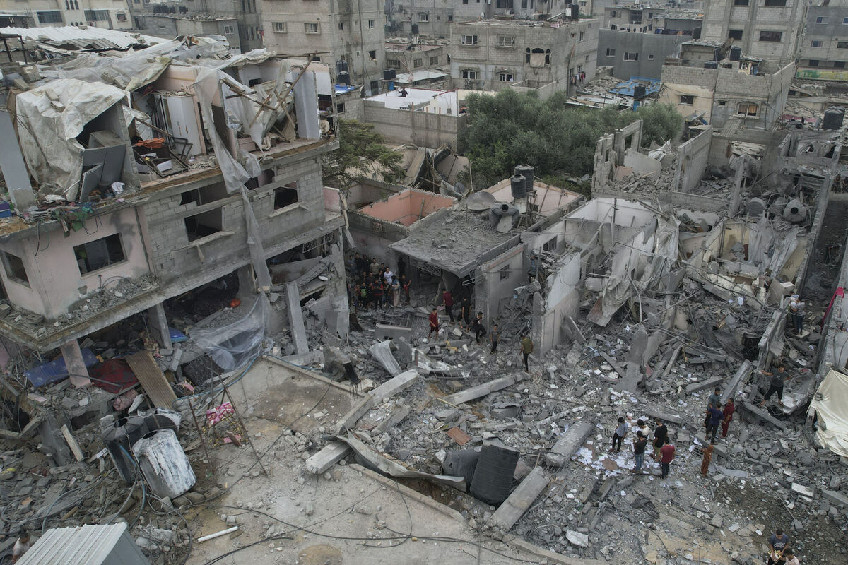 Palestinians walk about buildings destroyed in the Israeli bombardment in the Nusseirat refugee camp in the Gaza Strip.