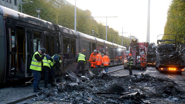 <p>Workers clearing debris from a burned-out bus and Luas tram on O'Connell Street in the wake of the violence scenes in Dublin city centre on  Thursday November 23. Picture: Brian Lawless/PA</p>