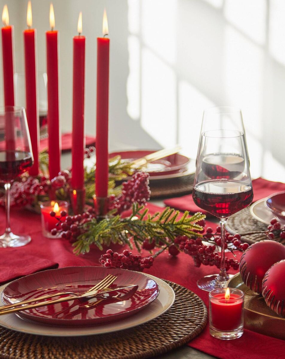 Red-themed tablescape: Gold cutlery set, €59.95, metallic angle plate, €9.95, dinner plate, €9.95, seven-taper holder, antique gold, €49, wine glasses, set of six, €44.95, jacquard runner, €24.95, all Meadows &amp; Byrne. 