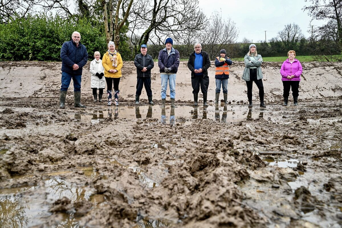 Residents in Ballinhassig, Cork stand together in front of an embankment they were forced to build themselves. Picture: Chani Anderson Residents in Ballinhassig, Cork stand together in front of an embankment they were forced to build themselves. Picture: Chani Anderson