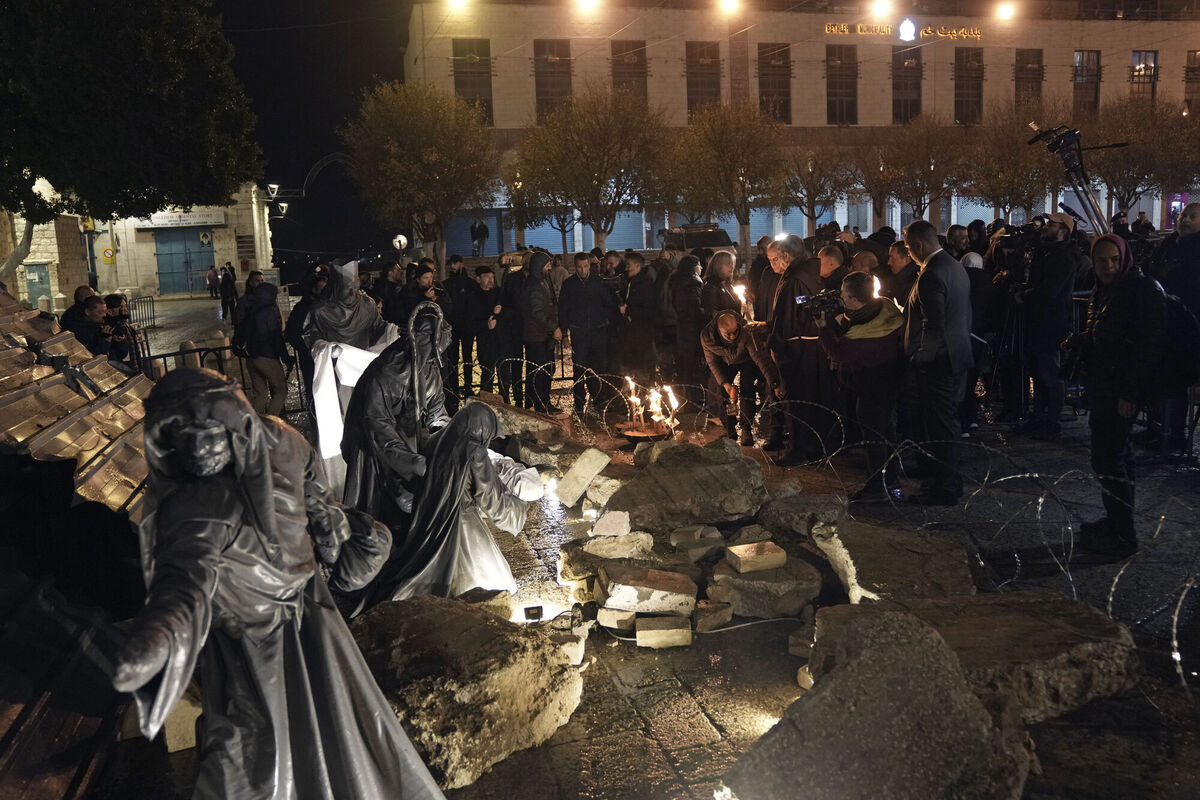 People light candles next to a nativity scene decorated to honor the victims in Gaza and asking for peace, displayed in Manger Square, adjacent to the Church of the Nativity, in the West Bank town of Bethlehem,